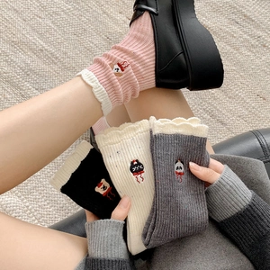 Detailaufnahme von Tierstickerei und weißem Spitzenrand an gestrickten Baumwollsocken