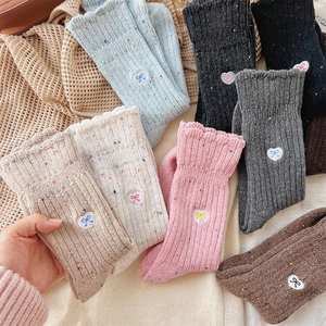 Close-up of nep yarn texture and bow heart embroidery on colorful warm wool socks