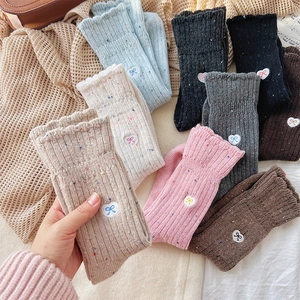 Detailed close-up of wool-blend crew socks with colorful yarn and heart bow embroidery