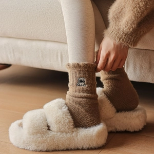 Detail of plush slippers and thermal socks with cute embroidered pug dog design