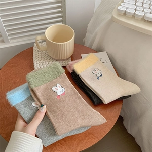 Détail de chaussettes à broderie lapin avec revers en fausse fourrure sur table
