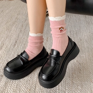 Detail von rosa gestreiften Socken mit Rüschensaum und süßer Hundestickerei am Fuß