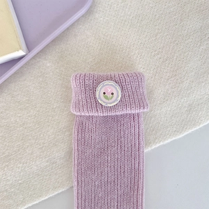 Close-up of lilac ribbed knit socks with a delicate floral badge and folded cuff