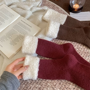 Détail de chaussettes en laine bordeaux et marron foncé avec revers en peluche douce
