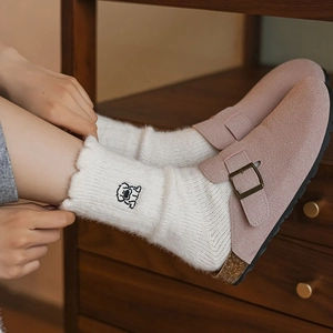 Close-up of cute dog embroidery on warm pink slippers and fuzzy white socks