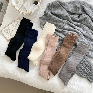 Detailed knit texture of six pairs of thick vertical ribbed winter crew socks in earth tones