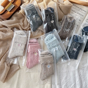 Close-up of assorted ribbed wool socks in zip-lock bags on a cozy knit blanket