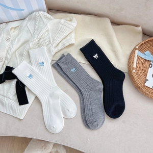 Détail de chaussettes en maille côtelée avec broderie de nœuds en noir et gris