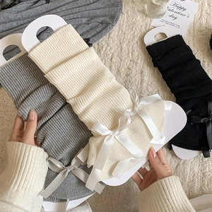 Detailed knit leg warmers with ribbons in grey, cream, and black colors