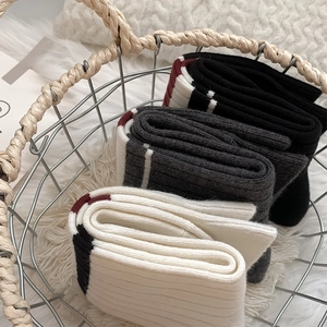 Detail of three pairs of ribbed knit crew socks with striped cuffs in a metal basket