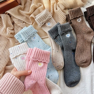 Detail of knit wool blend socks with heart bow embroidery and colorful speckled patterns