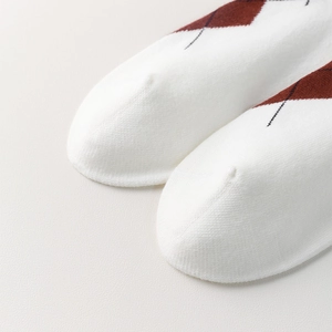 Close-up of white diamond pattern knee-high socks showing fine stitching and cotton texture