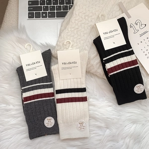 Detailed knit texture of three-pack striped wool blend socks on white faux fur carpet