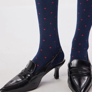 Gros plan de chaussettes bleues à pois rétro avec des escarpins noirs en cuir verni