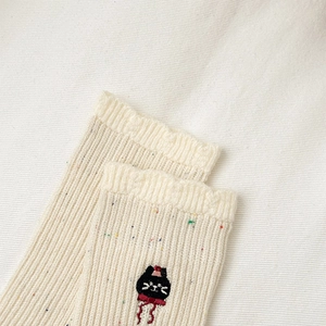 Detailansicht cremefarbener Stricksocken mit bunten Punkten und süßer Katzenstickerei