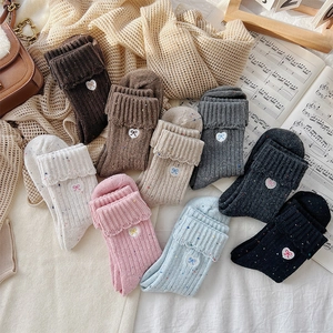 Detailed view of knitted wool socks with embroidered bow knots and folded cuffs in various colors