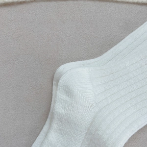 Vue détaillée de chaussettes en maille côtelée blanche montrant la couture du talon