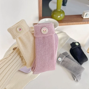 Detailed macro view of four colors of knitted socks with cute fruit button cuffs
