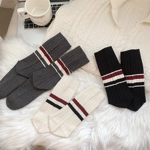 Detail view of ribbed knit mid-calf socks in grey, black, and beige with varsity stripes