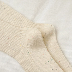 Nahaufnahme süßer cremefarbener Rippstrick-Socken mit buntem Nep-Garn und Stickerei