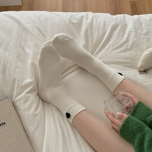 Close-up of cream knit socks with black heart detail in a cozy home lifestyle setting