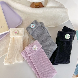 Detail of knit socks in pastel colors with decorative button fold-over cuffs