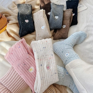 Detail of wool knit socks with colorful flecks and cute bow patches in soft cozy colors