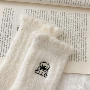 Close-up of white plush thermal socks with cute dog embroidery on a vintage book