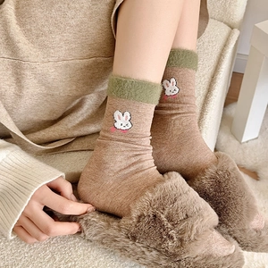 Détail de la broderie lapin sur chaussettes brunes avec revers en peluche verte et maille