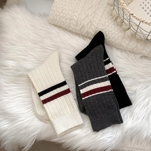 Close-up of thick knitted crew socks with stripes and ribbed texture on cozy background