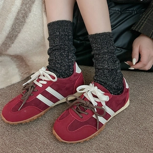 Gros plan de baskets en daim bordeaux avec doubles lacets et chaussettes en laine