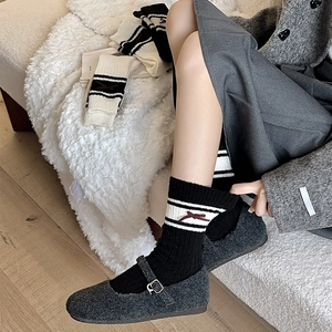 Detail of college style black crew socks with red bow and white stripes on gray shoes