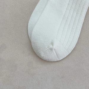Gros plan de chaussettes en maille côtelée blanche montrant la texture et les coutures
