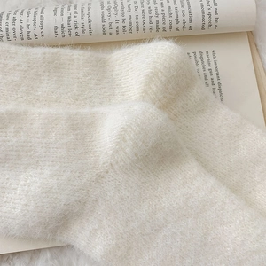Close-up of white fluffy thermal socks with soft texture on an open book background
