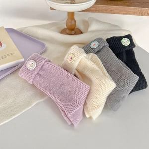 Close-up of knit beanies with decorative badges in purple, cream, gray, and black colors
