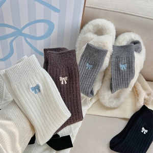 Détail de chaussettes en maille côtelée avec broderie nœud délicate aux tons chauds