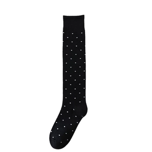 Chaussettes montantes noires à pois blancs et bords côtelés sur fond blanc pur