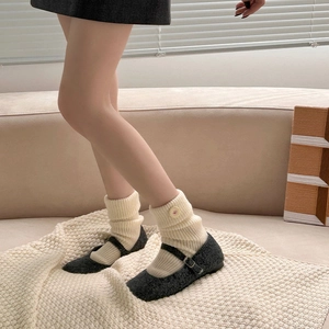 Detail of cream rib knit crew socks paired with dark grey Mary Jane shoes in warm setting