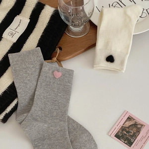 Detail of gray and cream mid-calf socks with small heart embroidery and striped knitwear