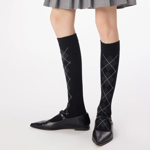 Close-up of black knee-high argyle socks with classic grey diamond knit patterns