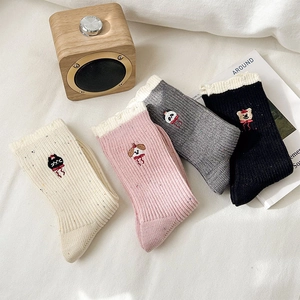 Detail der Tierstickerei und Spitzenkante an gesprenkelten Kaschmir-Mix Socken