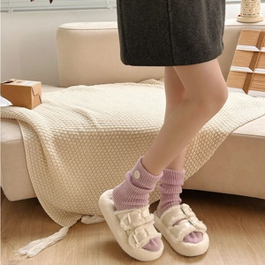 Detail of plush beige slipper with double metal buckles and purple knit socks
