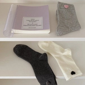 Detailed close-up of three pairs of knit mid-calf socks with cute 3D plush heart charms