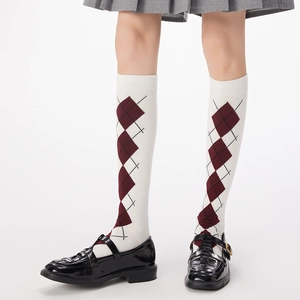 Detailed view of argyle patterned knee-high socks styled with a pleated skirt and shoes