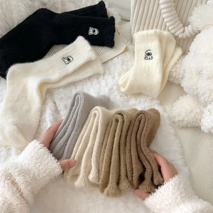 Close-up of cozy plush crew socks with cute dog embroidery in warm earthy colors