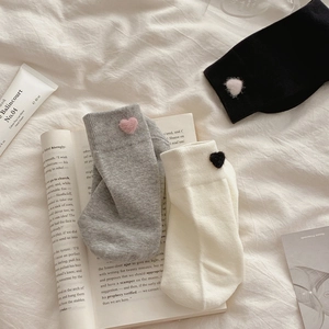 Detail of cotton socks with heart patches in grey, black and white on white fabric