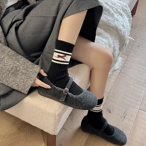 Detail of grey velvet Mary Janes and black knit socks with red bow jacquard