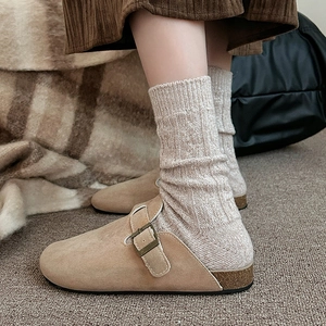 Détail de chaussettes en laine torsadée portées avec des mules à boucle style rétro