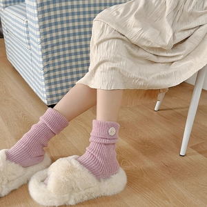 Detail of pink ribbed mid-calf sock with a small flower button patch and cozy home styling