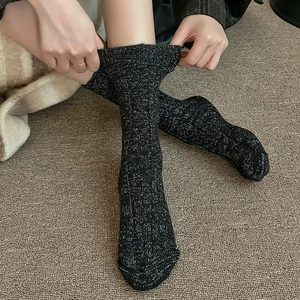 Gros plan de chaussettes en tricot de laine noire avec fils argentés et poignets élastiques